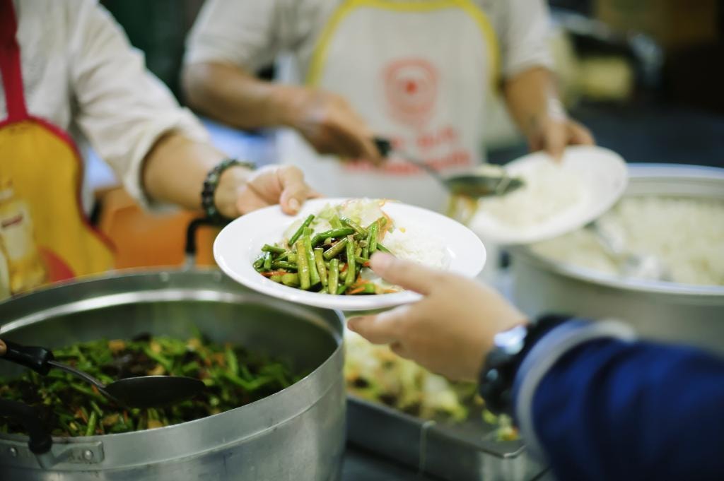 Volunteer serving a plate of fresh vegetables